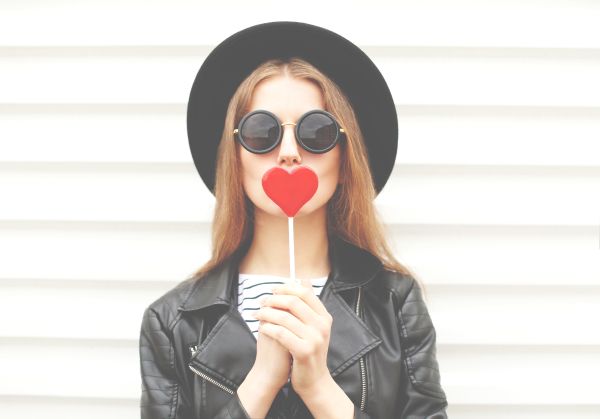 Millennial girl with heart-shaped lollipop